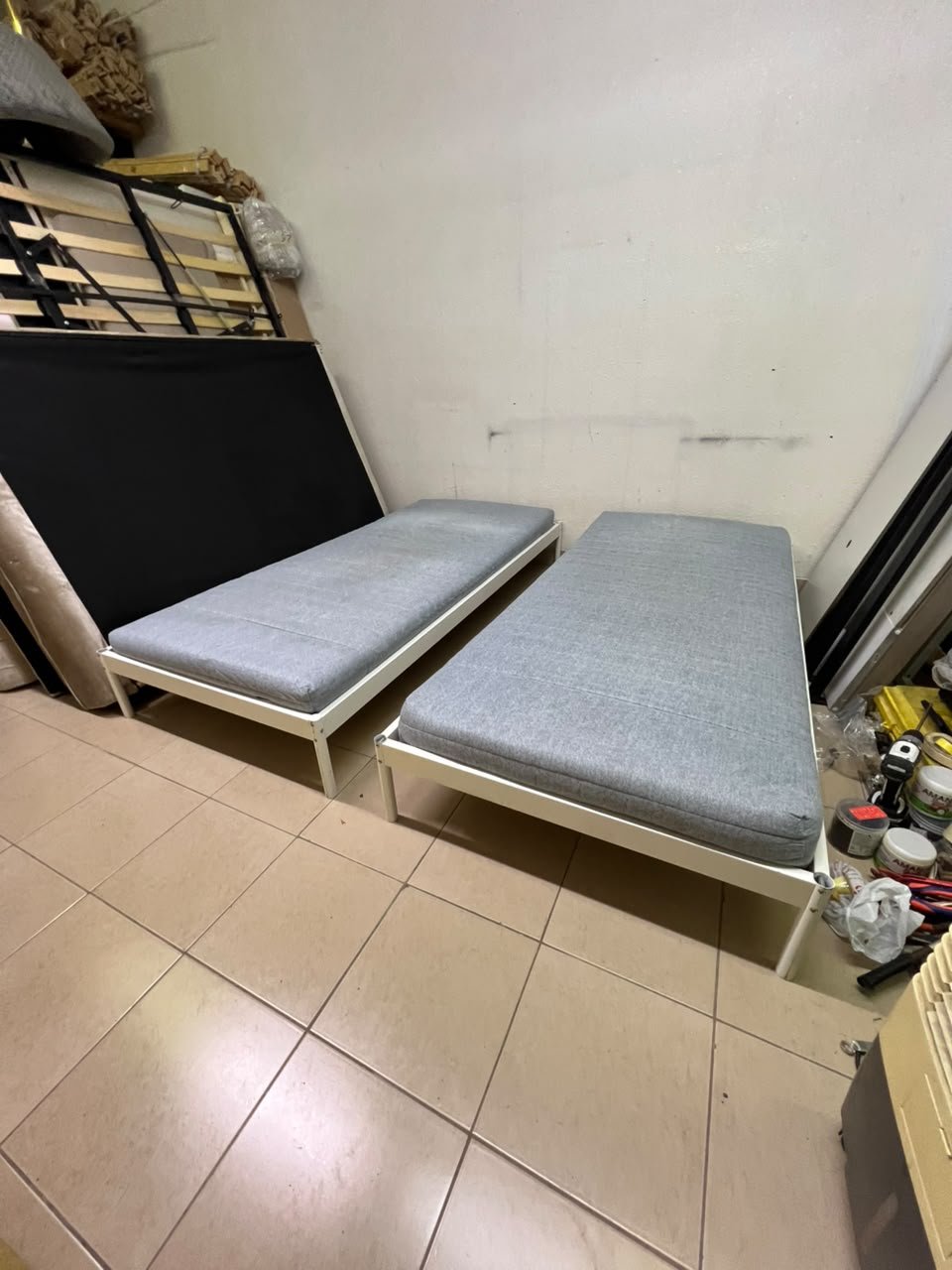 Two single beds with white metal frames, featuring lightweight foam mattresses in a light gray/blue color—similar to the ÅGOTNES foam mattress from IKEA.