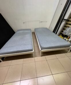 Two single beds with white metal frames, featuring lightweight foam mattresses in a light gray/blue color—similar to the ÅGOTNES foam mattress from IKEA. - Image 2