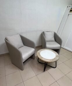 A seating set consisting of two individual grey chairs with square back cushions, with a small, round coffee table—featuring a white top and a black metal base—placed between them. - Image 2