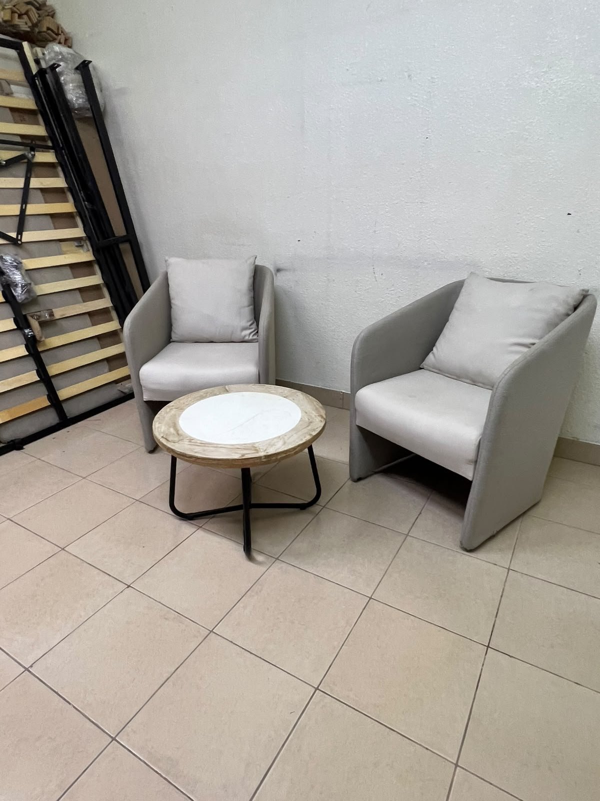 A seating set consisting of two individual grey chairs with square back cushions, with a small, round coffee table—featuring a white top and a black metal base—placed between them. - Image 3