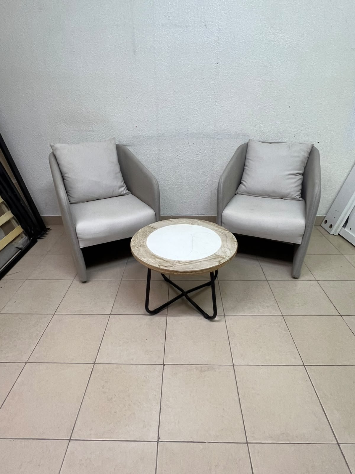 A seating set consisting of two individual grey chairs with square back cushions, with a small, round coffee table—featuring a white top and a black metal base—placed between them. - Image 6
