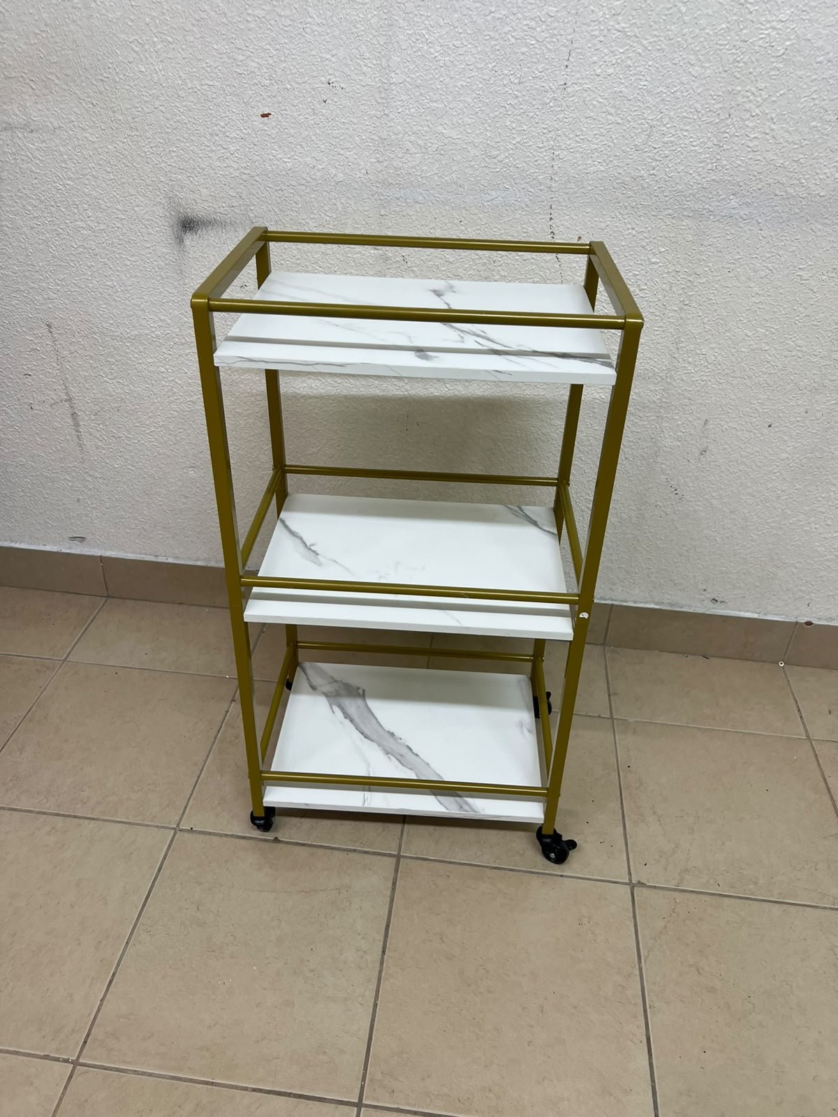 A 3-tier storage or serving cart on wheels, featuring a gold-colored metal frame and white, marble-design shelves. - Image 4