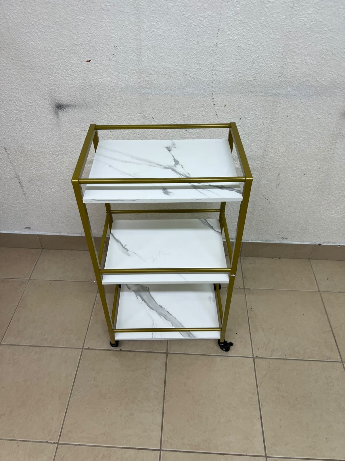 A 3-tier storage or serving cart on wheels, featuring a gold-colored metal frame and white, marble-design shelves. - Image 5