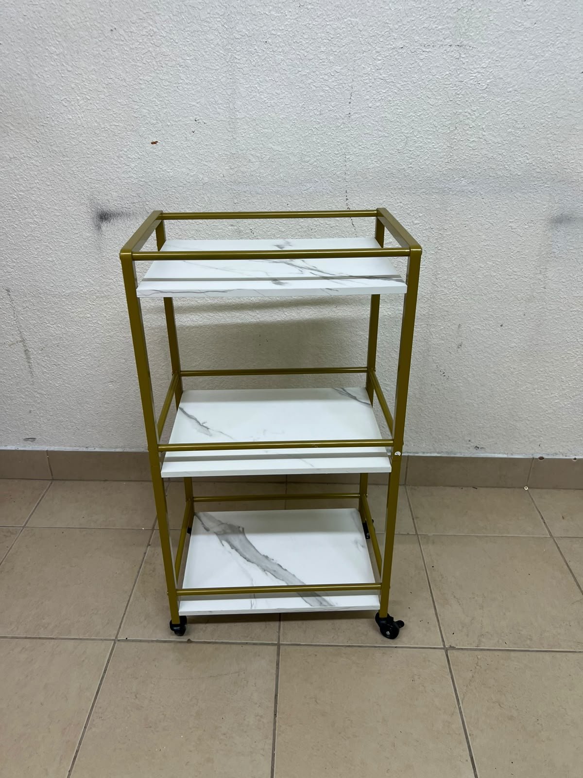 A 3-tier storage or serving cart on wheels, featuring a gold-colored metal frame and white, marble-design shelves. - Image 6