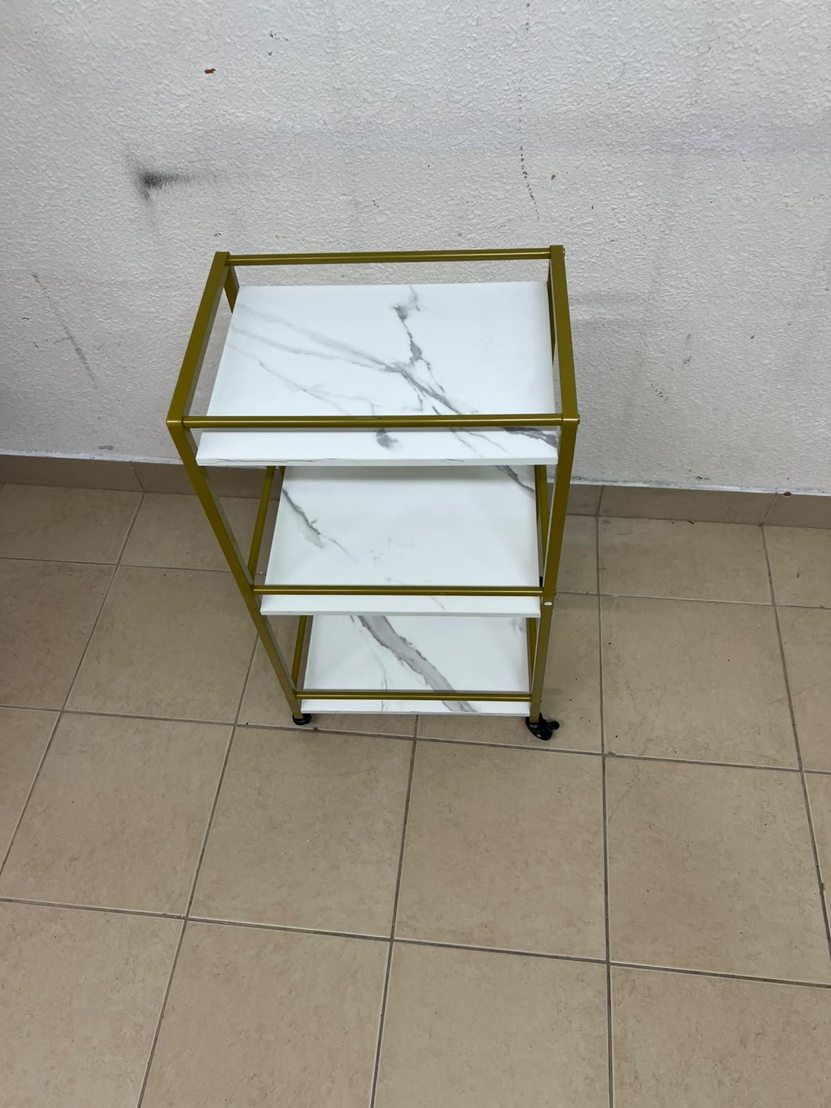 A 3-tier storage or serving cart on wheels, featuring a gold-colored metal frame and white, marble-design shelves. - Image 8