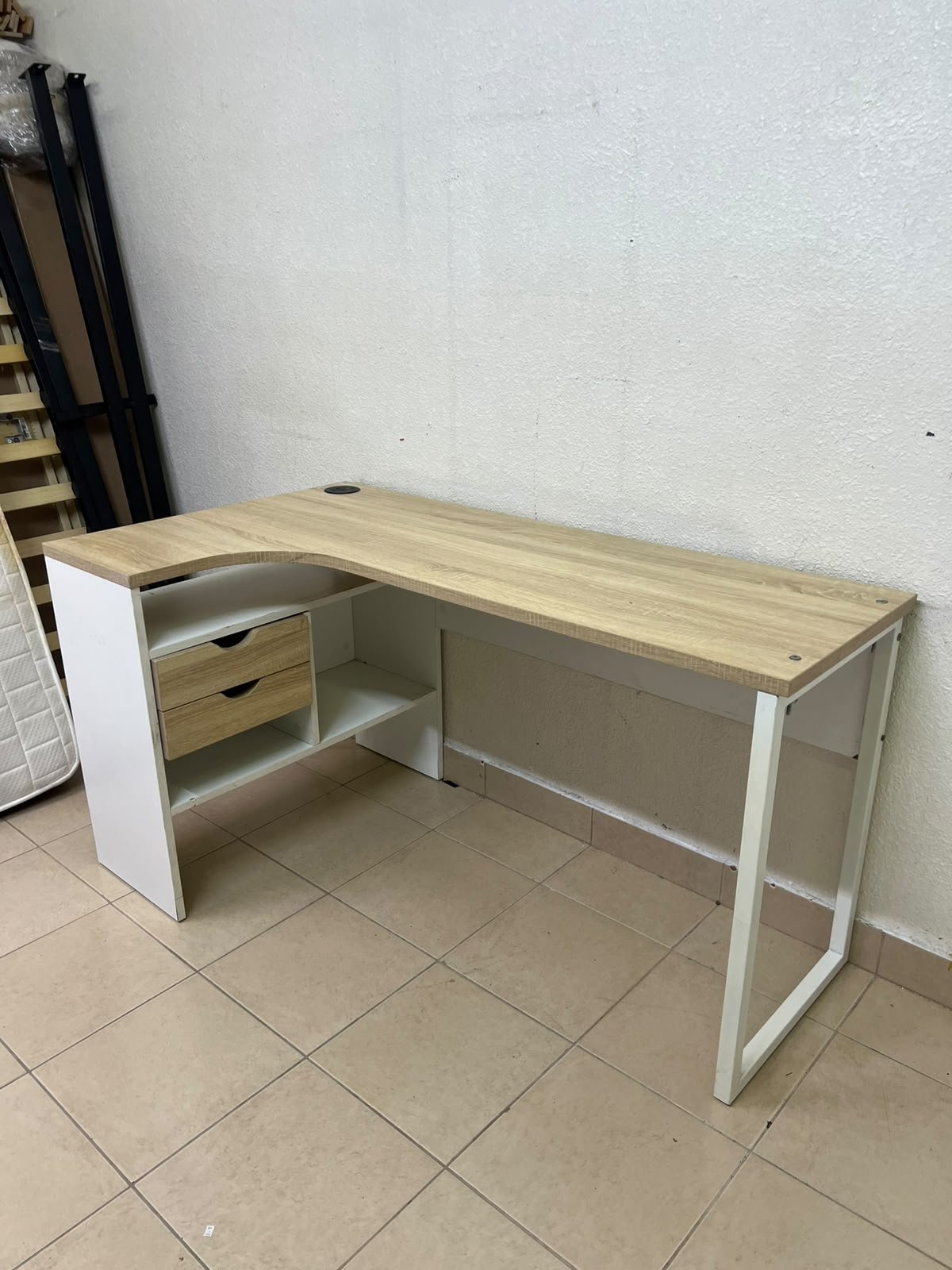 An L-shaped corner desk in white, featuring a light wood-tone (oak) surface and two drawers, complete with side storage units that include two drawers and open shelving.