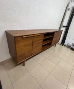 A walnut-wood TV unit or media cabinet from Home Centre, featuring open central shelving, enclosed side cabinets, and slender, tapered legs.