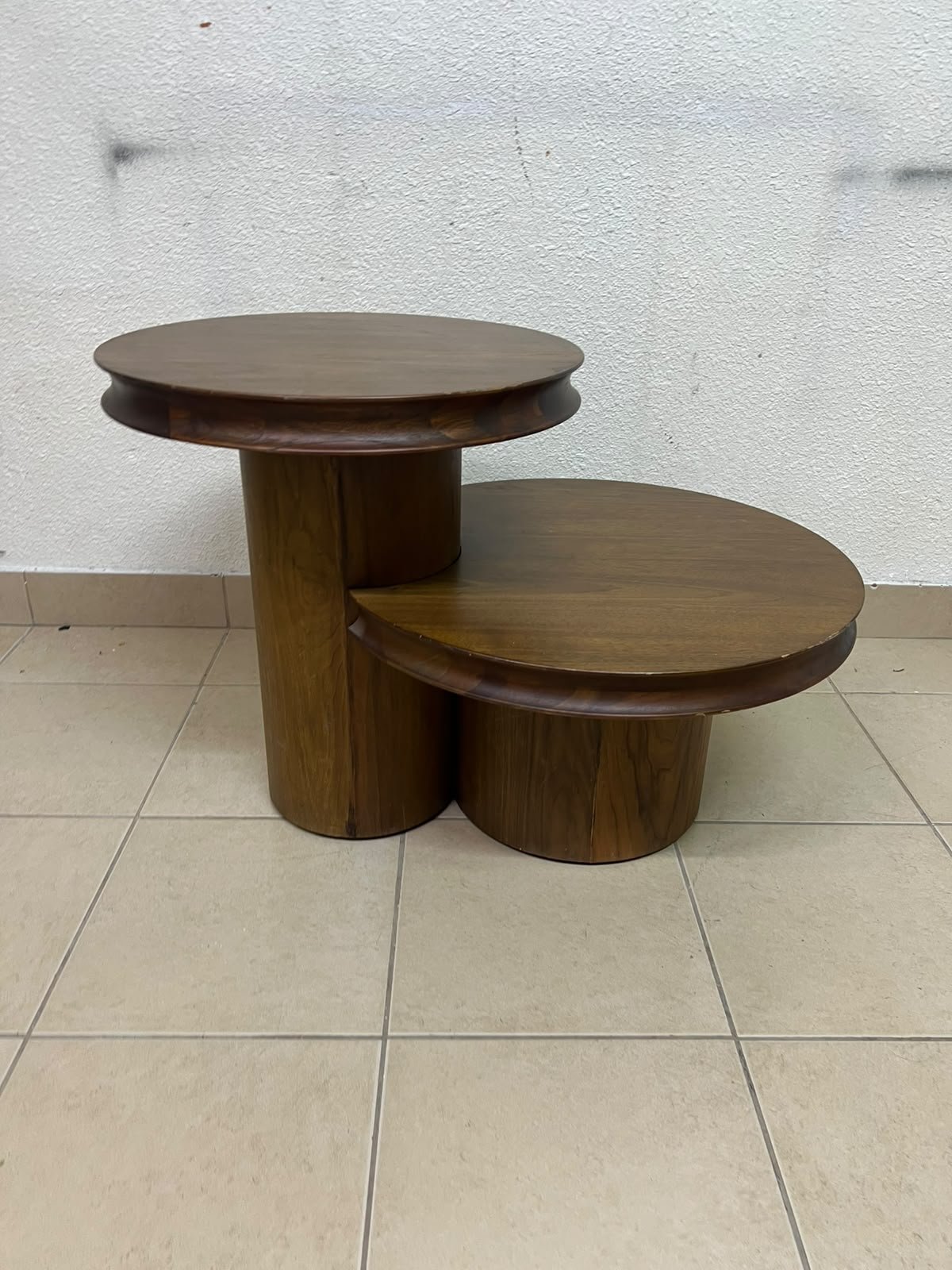 A two-tier side table crafted from natural walnut, featuring a mid-century inspired design—reminiscent of iconic pieces such as the "Oro" table from Crate & Barrel or Scandinavian-style tiered tables.
