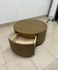 A round, dark oak-colored wooden coffee table, featuring an elegant, modern design with a curved storage drawer equipped with concealed or recessed handles.