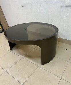 A round coffee table featuring a curved base in a bronze or metallic brown finish, topped with a smoked (tempered) glass surface.
