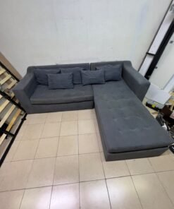 A dark gray L-shaped sectional sofa with a modern design, featuring a long chaise lounge, a tufted seat cushion, and additional back cushions. - Image 9