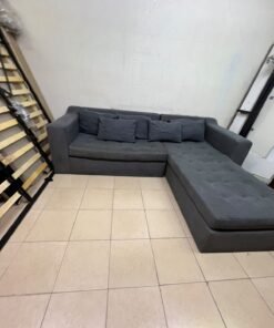 A dark gray L-shaped sectional sofa with a modern design, featuring a long chaise lounge, a tufted seat cushion, and additional back cushions. - Image 12