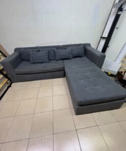 A dark gray L-shaped sectional sofa with a modern design, featuring a long chaise lounge, a tufted seat cushion, and additional back cushions. - Image 2