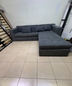 A dark gray L-shaped sectional sofa with a modern design, featuring a long chaise lounge, a tufted seat cushion, and additional back cushions. - Image 3