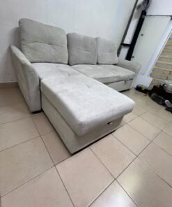 # Convertible Fabric Corner Sofa Bed with Chaise Longue and Storage – Home Box UAE Upgrade your living room with this practical and stylish convertible fabric corner sofa bed from Home Box UAE, designed to combine comfort, functionality, and modern elegance in one versatile piece of furniture. Featuring a spacious three-seater design with an extended chaise longue, this sofa provides plenty of room for relaxing, watching television, entertaining guests, or spending quality time with family. Its attractive fabric upholstery adds a warm and welcoming touch to any living space, making it an excellent choice for apartments, villas, guest rooms, and modern homes. One of the main advantages of this corner sofa is its convertible sofa-bed function, which allows you to transform the seating area into a comfortable sleeping space whenever needed. This practical feature makes it especially suitable for homes where extra sleeping arrangements are occasionally required without sacrificing valuable floor space. Whether you have overnight visitors or simply want a comfortable place to stretch out and relax, this multifunctional design offers flexibility for everyday living. The extended chaise longue provides additional legroom, allowing you to sit back comfortably, read a book, enjoy your favourite shows, or take a relaxing afternoon nap. The spacious seating arrangement makes it suitable for individuals, couples, and families looking for furniture that offers both convenience and comfort. Another useful feature is the integrated storage compartment, which provides extra room for keeping blankets, pillows, bedsheets, cushions, and other household essentials neatly organised and within easy reach. With its combination of seating, sleeping, and storage functions, this fabric corner sofa is an excellent space-saving solution for contemporary interiors. Its versatile design allows it to serve as the main sofa in a living room while also functioning as a guest bed and a convenient storage unit. The fabric finish complements a variety of interior styles, including modern, minimalist, contemporary, and casual home décor, making it easy to incorporate into different living environments. If you are searching for an affordable and functional sofa bed in Dubai, Sharjah, or Ajman, this Home Box-style convertible corner sofa is worth considering for its practical features and versatile use. It is particularly suitable for people furnishing a new apartment, upgrading their existing living room, or looking for multifunctional furniture that makes the most of available space. At Yahya Used Furniture, we offer a wide selection of second-hand furniture for customers looking for practical home furnishing solutions at affordable prices. If you are interested in buying a used corner sofa, sofa bed, chaise longue, or other living room furniture, explore our available collection to discover options that suit your space and budget. Choose a sofa that brings together comfortable seating, flexible sleeping arrangements, and useful storage in one convenient design. This convertible fabric corner sofa bed is a practical furniture choice for making your living room more comfortable, organised, and ready for everyday life. - Image 12