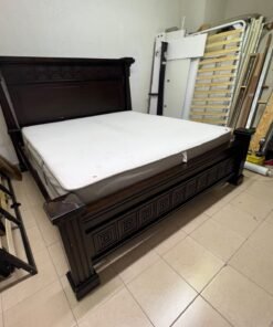 Large, classic double bed (king-size) with mattress, crafted from dark wood and featuring a headboard and footboard adorned with square-patterned detailing.