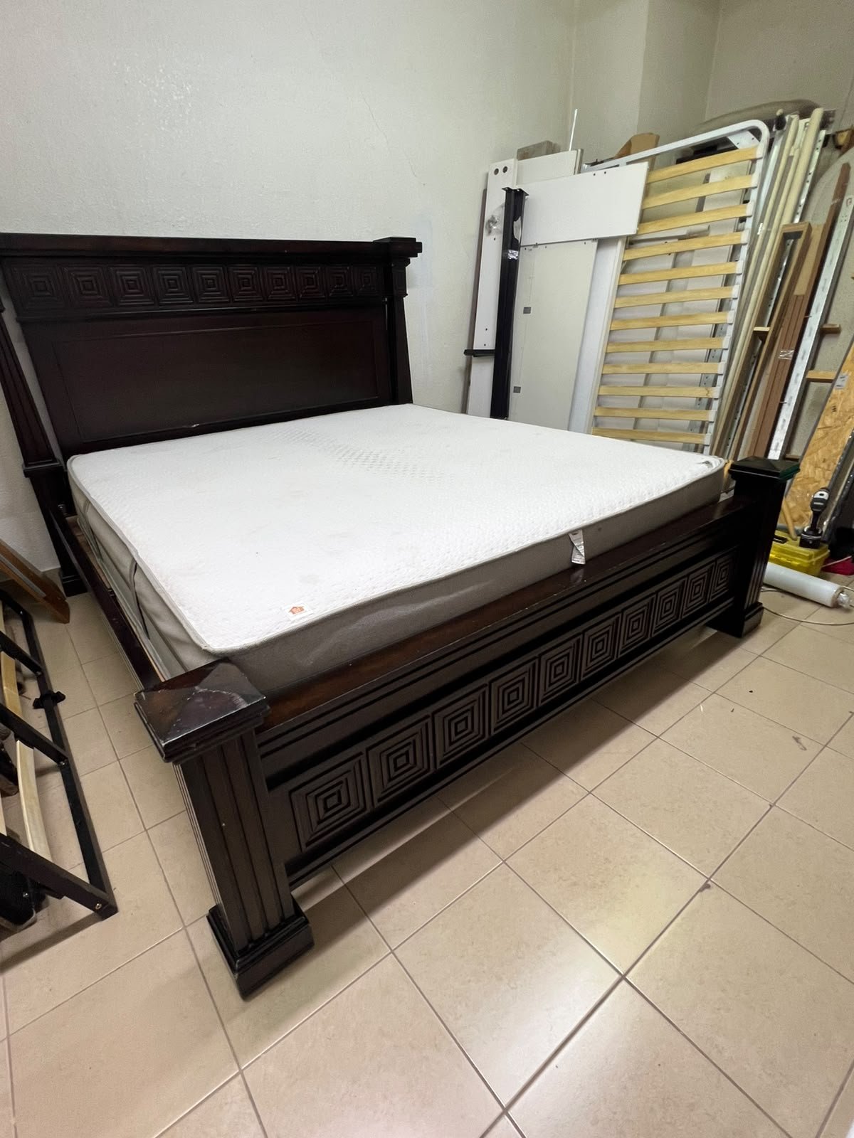 Large, classic double bed (king-size) with mattress, crafted from dark wood and featuring a headboard and footboard adorned with square-patterned detailing.