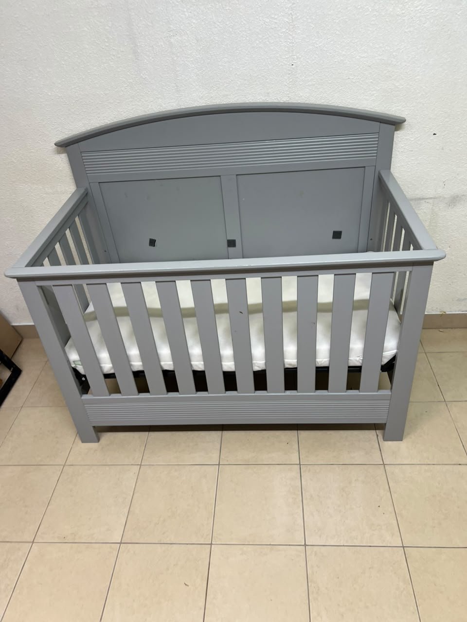 A convertible crib (such as the Serta Barrett model or the Dylan crib by Juniors, available at Centrepoint UAE) in an elegant gray color, featuring a classic, adjustable design that adapts to the various stages of a child's growth. - Image 9