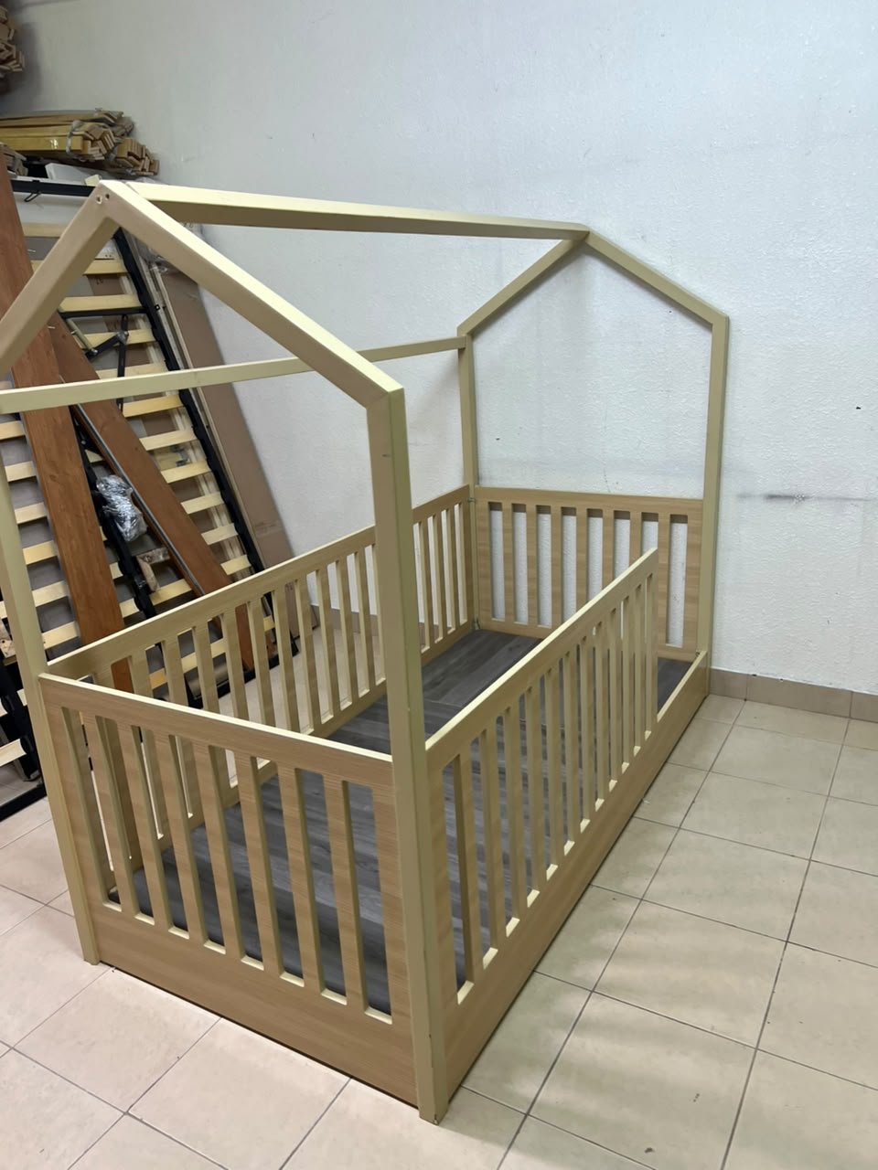 A wooden Montessori house bed—a floor-level or low-profile bed featuring side guardrails—designed to ensure safety while fostering the child's freedom of movement and independence. - Image 9