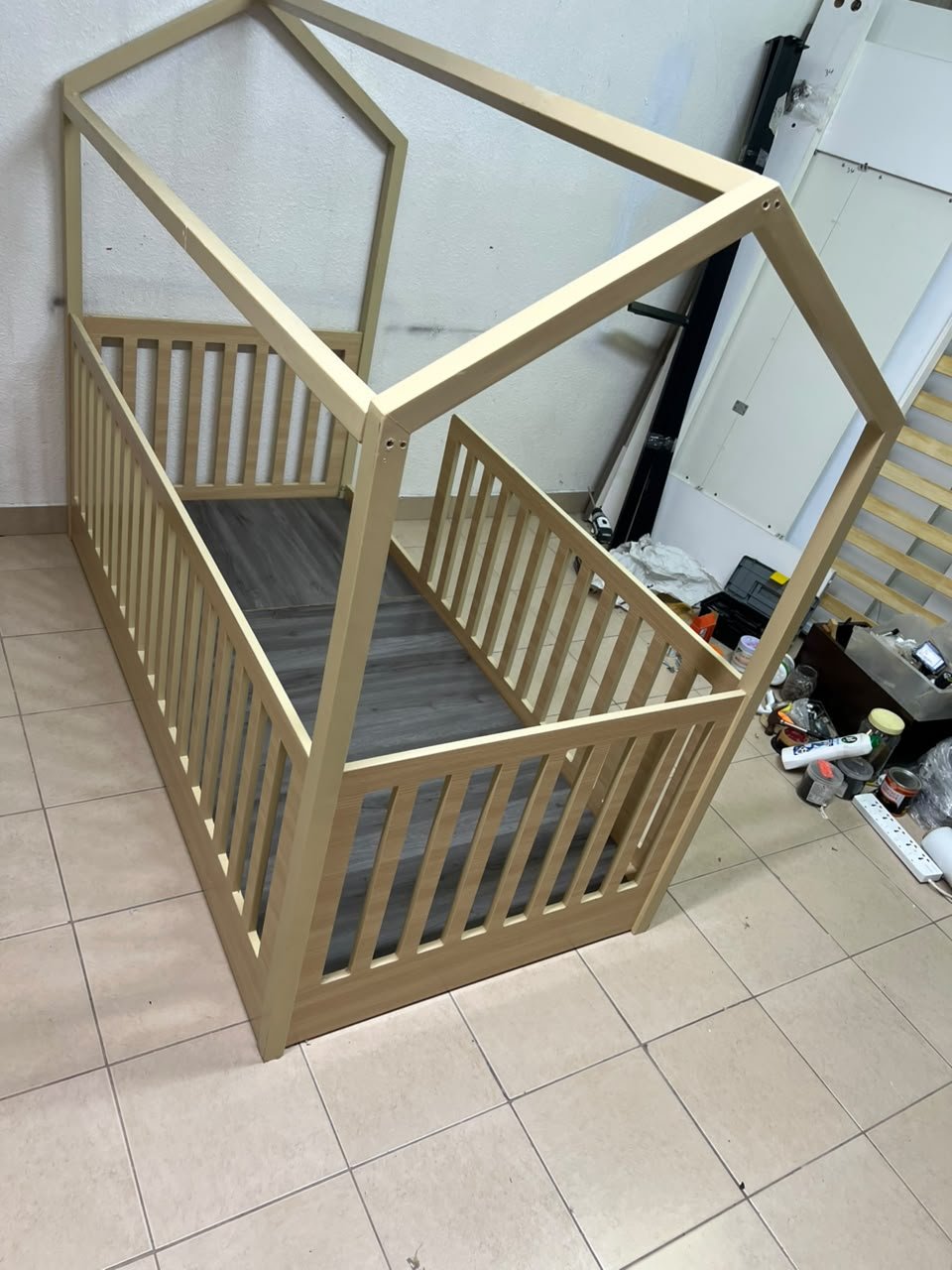A wooden Montessori house bed—a floor-level or low-profile bed featuring side guardrails—designed to ensure safety while fostering the child's freedom of movement and independence. - Image 10