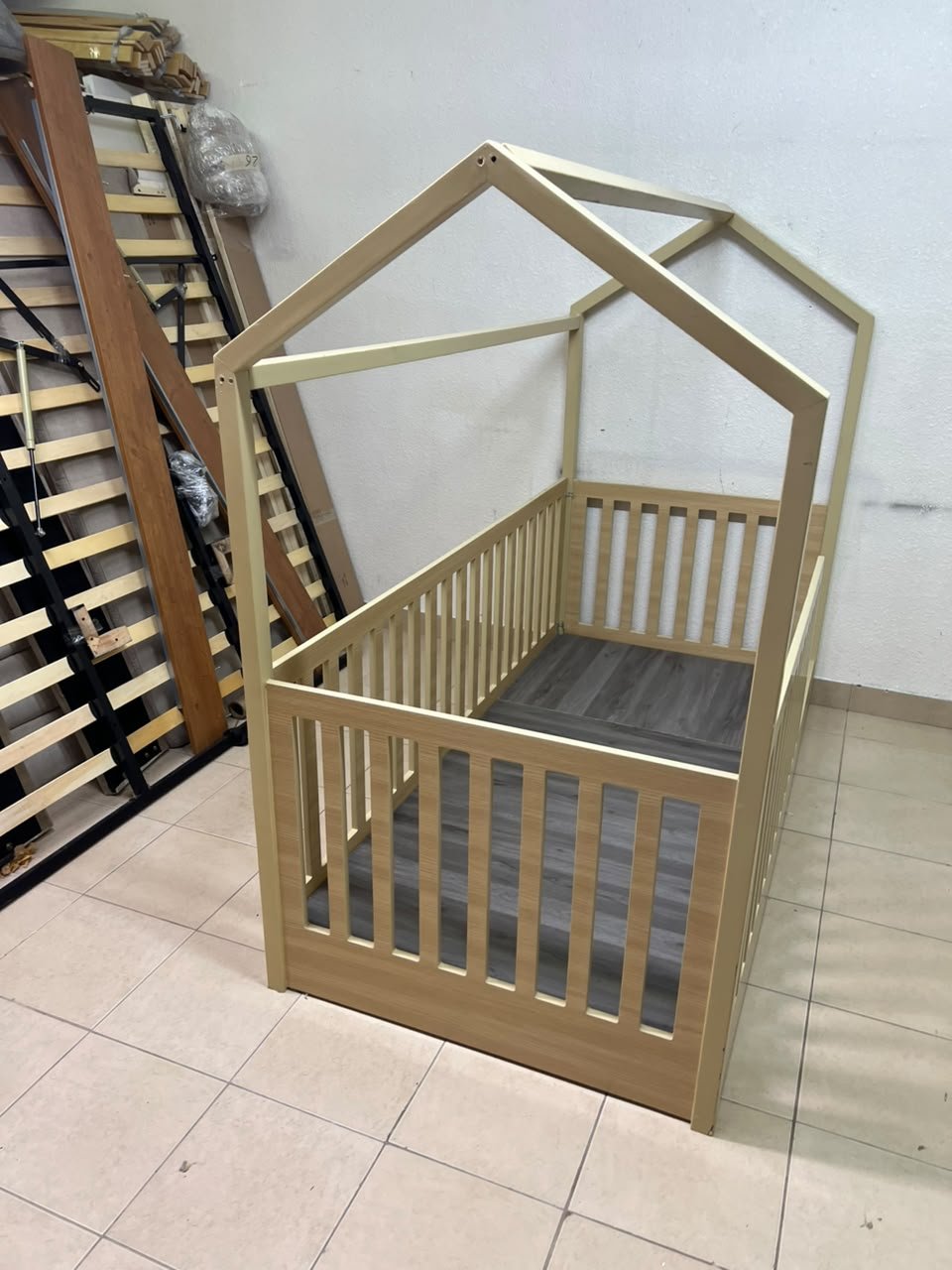 A wooden Montessori house bed—a floor-level or low-profile bed featuring side guardrails—designed to ensure safety while fostering the child's freedom of movement and independence. - Image 2