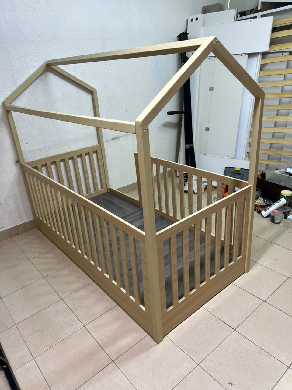 A wooden Montessori house bed—a floor-level or low-profile bed featuring side guardrails—designed to ensure safety while fostering the child's freedom of movement and independence. - Image 3