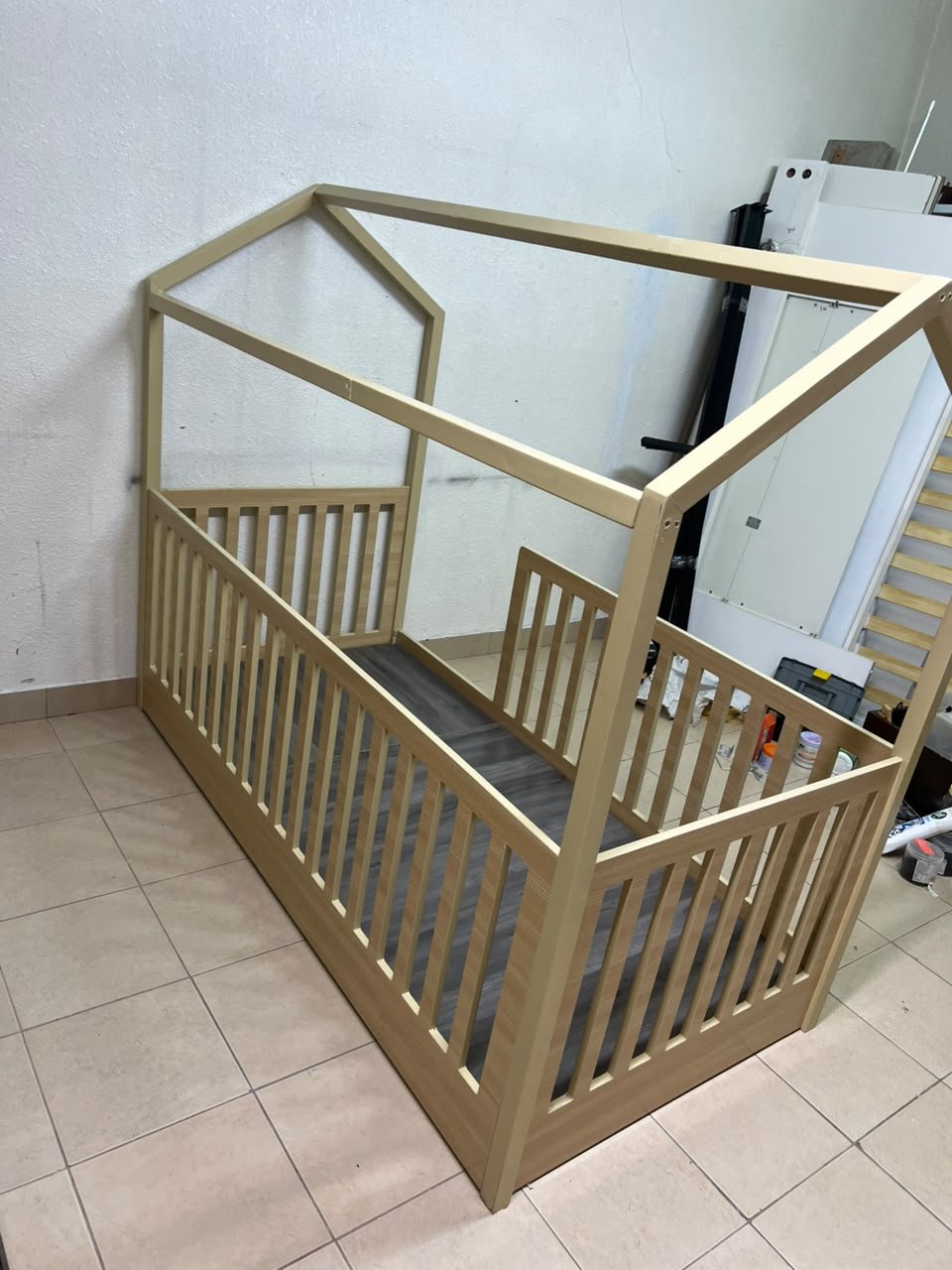 A wooden Montessori house bed—a floor-level or low-profile bed featuring side guardrails—designed to ensure safety while fostering the child's freedom of movement and independence. - Image 4
