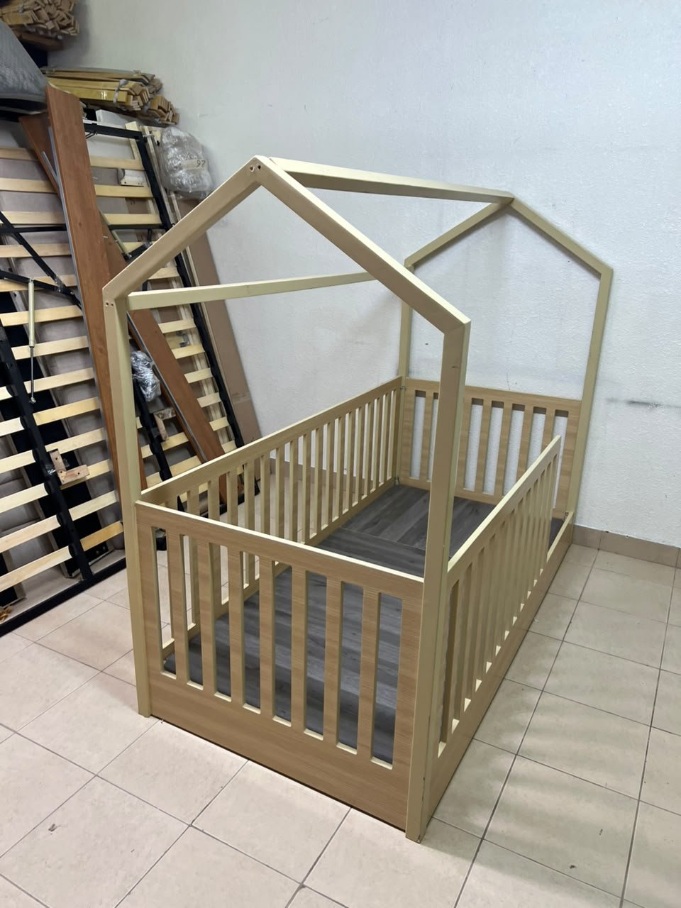A wooden Montessori house bed—a floor-level or low-profile bed featuring side guardrails—designed to ensure safety while fostering the child's freedom of movement and independence. - Image 5