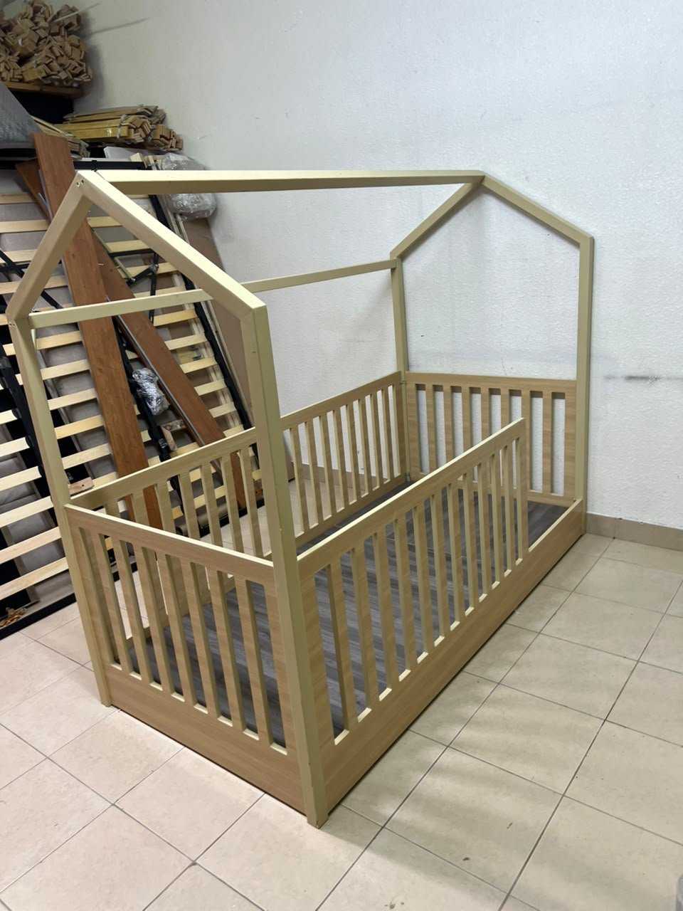 A wooden Montessori house bed—a floor-level or low-profile bed featuring side guardrails—designed to ensure safety while fostering the child's freedom of movement and independence.
