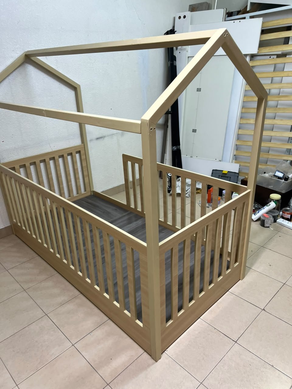 A wooden Montessori house bed—a floor-level or low-profile bed featuring side guardrails—designed to ensure safety while fostering the child's freedom of movement and independence. - Image 7