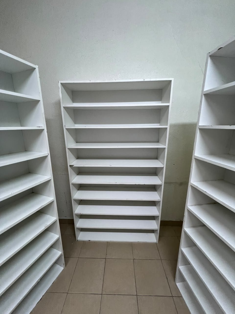 Three white open shelving/display units, constructed from wood, melamine, or MDF, featuring multi-level shelves. - Image 4