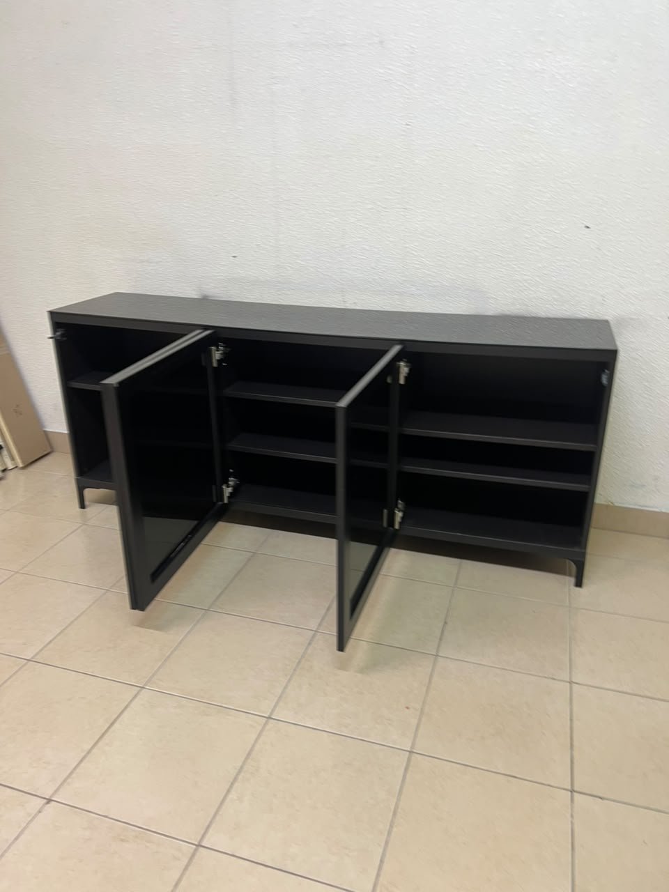 A cabinet (such as a TV stand or sideboard) that appears as a glossy black storage unit with three doors and slender legs; it bears a strong resemblance to the IKEA BESTÅ collection (specifically the Selsviken/Stubbarp combination in black-brown with high-gloss doors). - Image 2