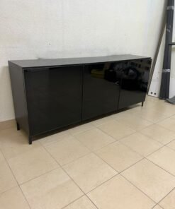 A cabinet (such as a TV stand or sideboard) that appears as a glossy black storage unit with three doors and slender legs; it bears a strong resemblance to the IKEA BESTÅ collection (specifically the Selsviken/Stubbarp combination in black-brown with high-gloss doors).