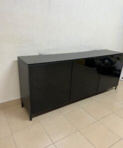 A cabinet (such as a TV stand or sideboard) that appears as a glossy black storage unit with three doors and slender legs; it bears a strong resemblance to the IKEA BESTÅ collection (specifically the Selsviken/Stubbarp combination in black-brown with high-gloss doors). - Image 5