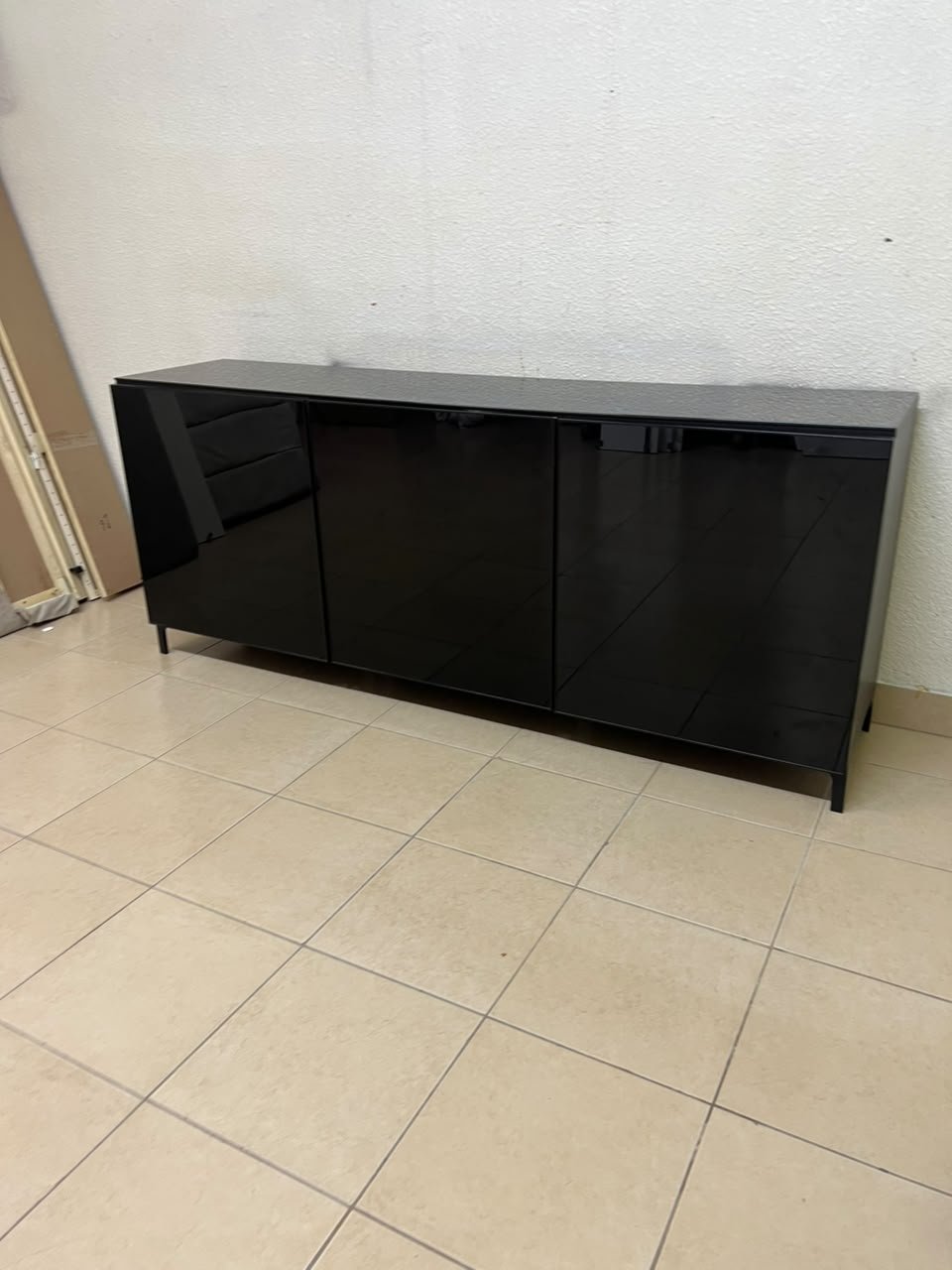 A cabinet (such as a TV stand or sideboard) that appears as a glossy black storage unit with three doors and slender legs; it bears a strong resemblance to the IKEA BESTÅ collection (specifically the Selsviken/Stubbarp combination in black-brown with high-gloss doors). - Image 6