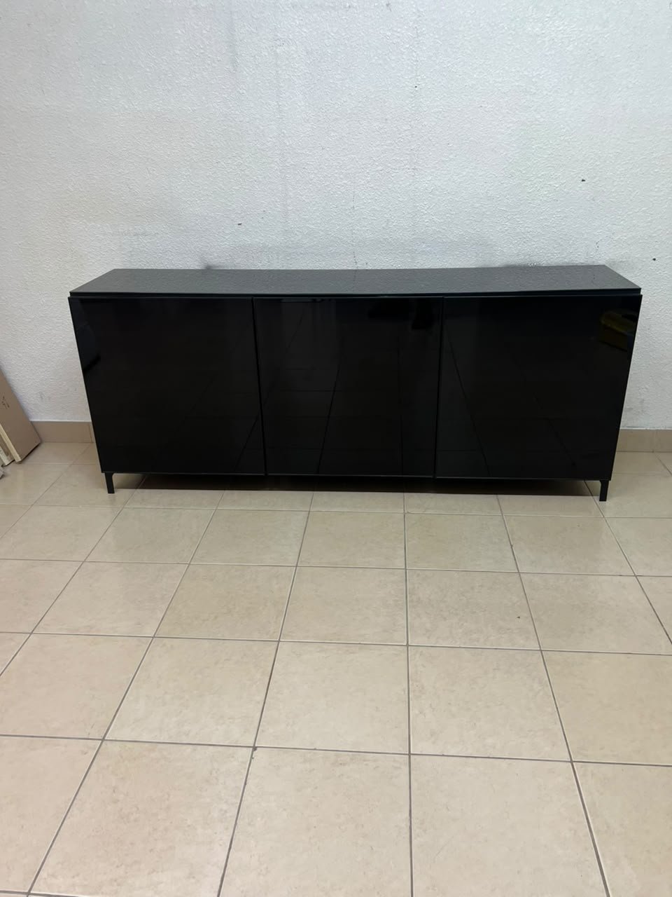 A cabinet (such as a TV stand or sideboard) that appears as a glossy black storage unit with three doors and slender legs; it bears a strong resemblance to the IKEA BESTÅ collection (specifically the Selsviken/Stubbarp combination in black-brown with high-gloss doors). - Image 7