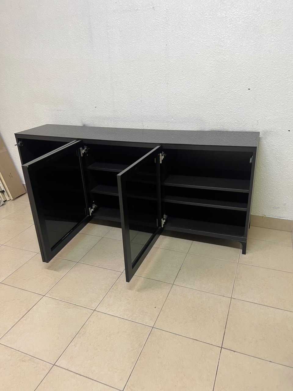 A cabinet (such as a TV stand or sideboard) that appears as a glossy black storage unit with three doors and slender legs; it bears a strong resemblance to the IKEA BESTÅ collection (specifically the Selsviken/Stubbarp combination in black-brown with high-gloss doors). - Image 9