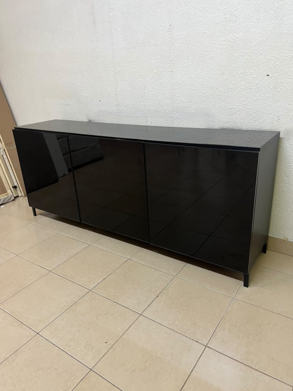 A cabinet (such as a TV stand or sideboard) that appears as a glossy black storage unit with three doors and slender legs; it bears a strong resemblance to the IKEA BESTÅ collection (specifically the Selsviken/Stubbarp combination in black-brown with high-gloss doors). - Image 11