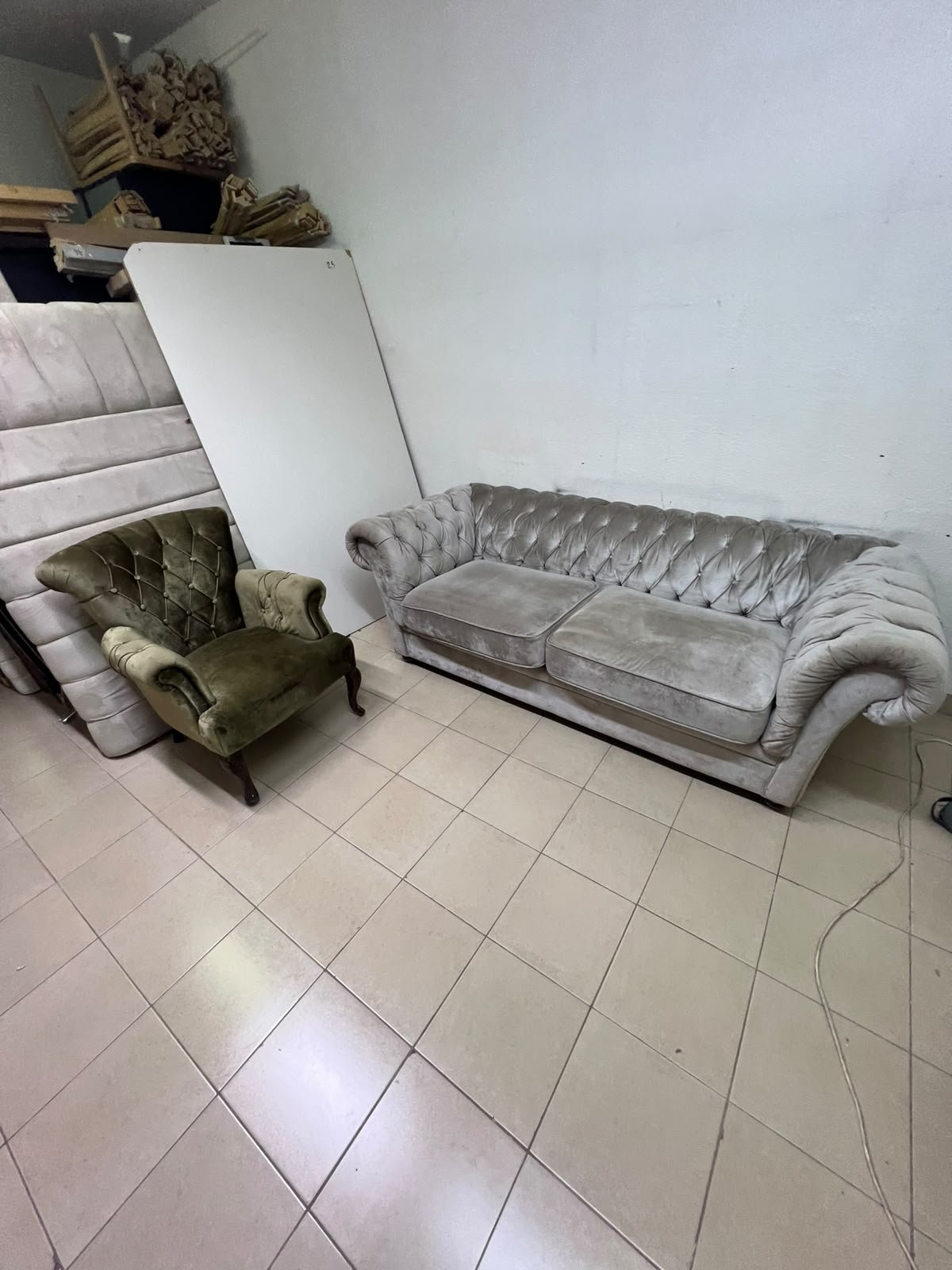 Classic Chesterfield-style furniture upholstered in velvet, featuring a long grey or silver sofa with a button-tufted backrest, accompanied by a matching armchair (fauteuil) in a dark green or olive shade, sharing the same plush, classic design.