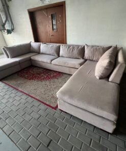 A U-shaped sectional sofa upholstered in beige or light gray fabric, featuring separate backrest cushions and two chaise longue/footrest sections on the sides. - Image 9