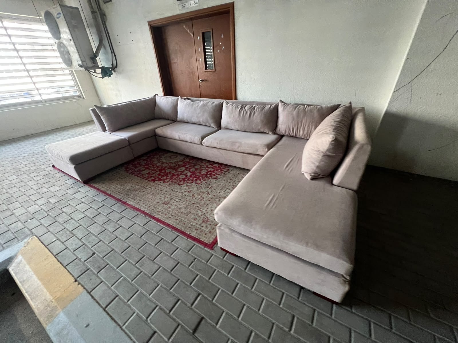 A U-shaped sectional sofa upholstered in beige or light gray fabric, featuring separate backrest cushions and two chaise longue/footrest sections on the sides. - Image 9