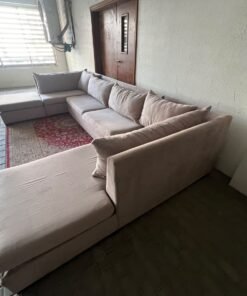 A U-shaped sectional sofa upholstered in beige or light gray fabric, featuring separate backrest cushions and two chaise longue/footrest sections on the sides. - Image 2