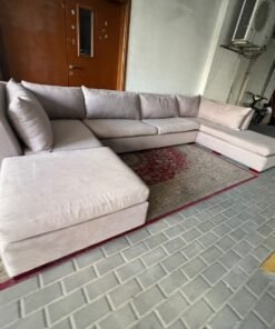 A U-shaped sectional sofa upholstered in beige or light gray fabric, featuring separate backrest cushions and two chaise longue/footrest sections on the sides. - Image 4