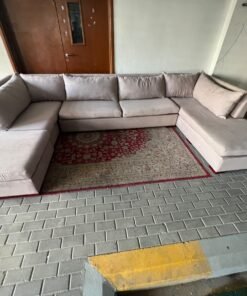 A U-shaped sectional sofa upholstered in beige or light gray fabric, featuring separate backrest cushions and two chaise longue/footrest sections on the sides. - Image 10