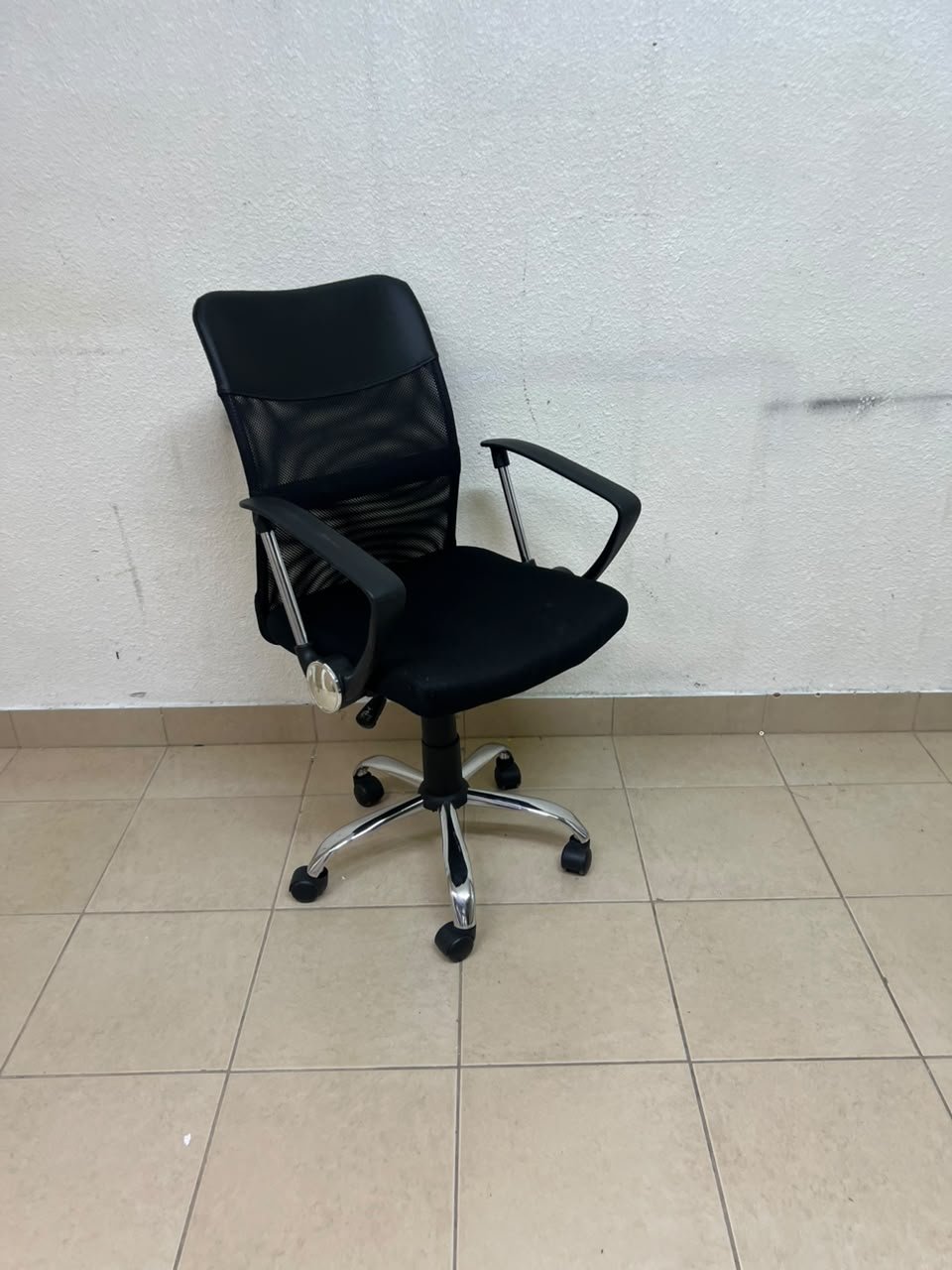 A black office chair featuring a comfortable mesh back, a chrome metal base with casters, armrests, and adjustable height.