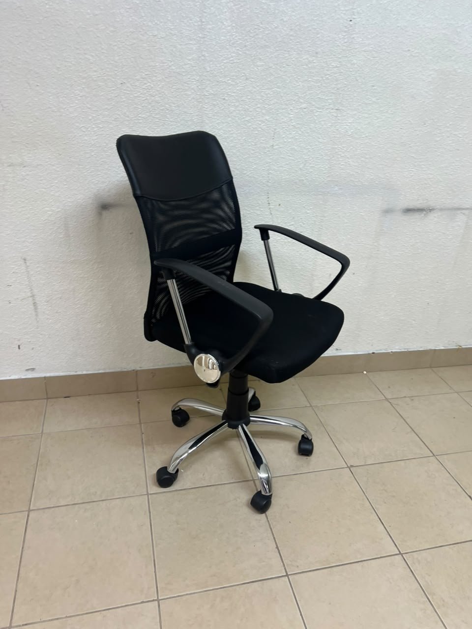 A black office chair featuring a comfortable mesh back, a chrome metal base with casters, armrests, and adjustable height. - Image 9