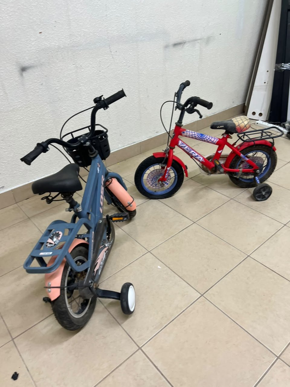 Two children’s bicycles in different colors (blue and red), equipped with training wheels and front baskets. - Image 7