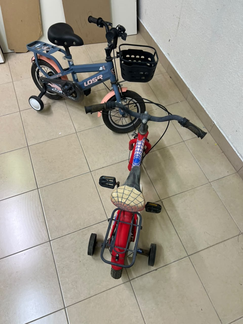 Two children’s bicycles in different colors (blue and red), equipped with training wheels and front baskets. - Image 10