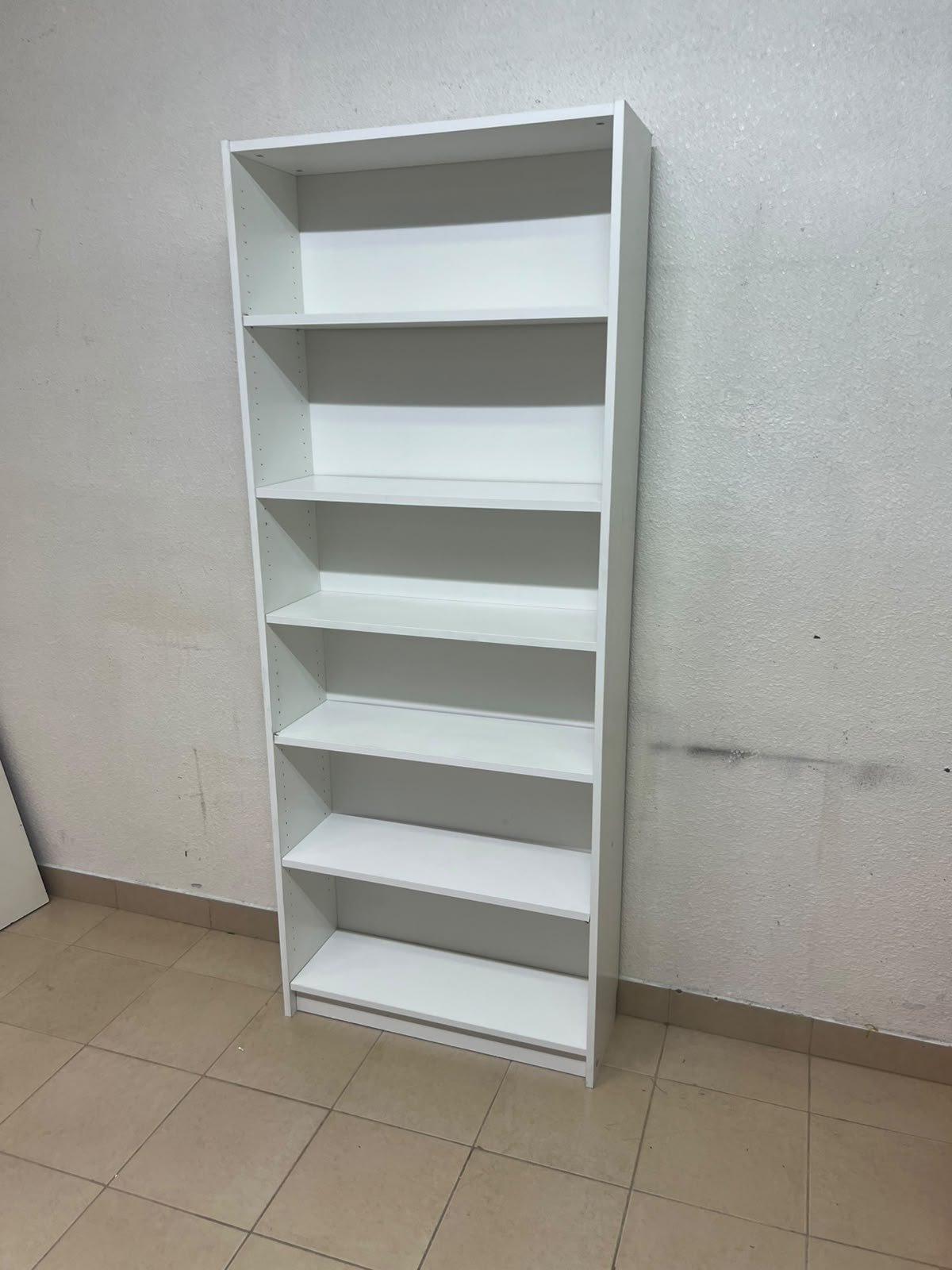 A white bookcase that looks similar to an IKEA BILLY bookcase or other comparable multi-shelf storage units. - Image 6