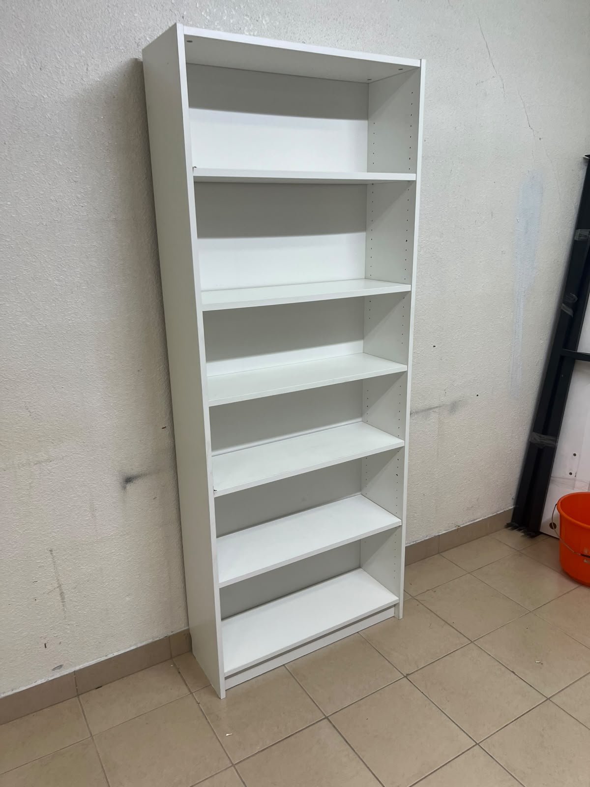 A white bookcase that looks similar to an IKEA BILLY bookcase or other comparable multi-shelf storage units. - Image 2